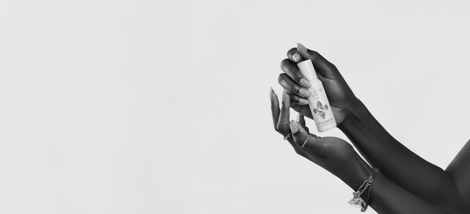 Black and white photograph of hands holding a Superior fragrance bottle